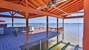 Una terraza techada con techo de madera, una mesa, sillas y vista al agua.