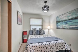 A bedroom with a bed, a window with blinds, a wall-mounted lamp, and a painting. - Charming Rochester Home - 2 Mi to Mayo Clinic! (Rochester)