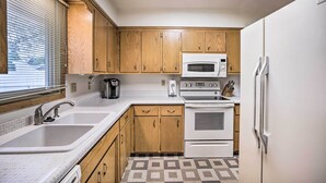 A kitchen with wooden cabinets, a white refrigerator, a microwave, a stove, and a sink.