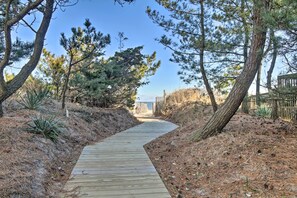 A wooden boardwalk leading through a natural area with pine trees and dry grass. - Bay-view Retreat w/ 5 Balconies in Bethany Beach! (Bethany Beach)