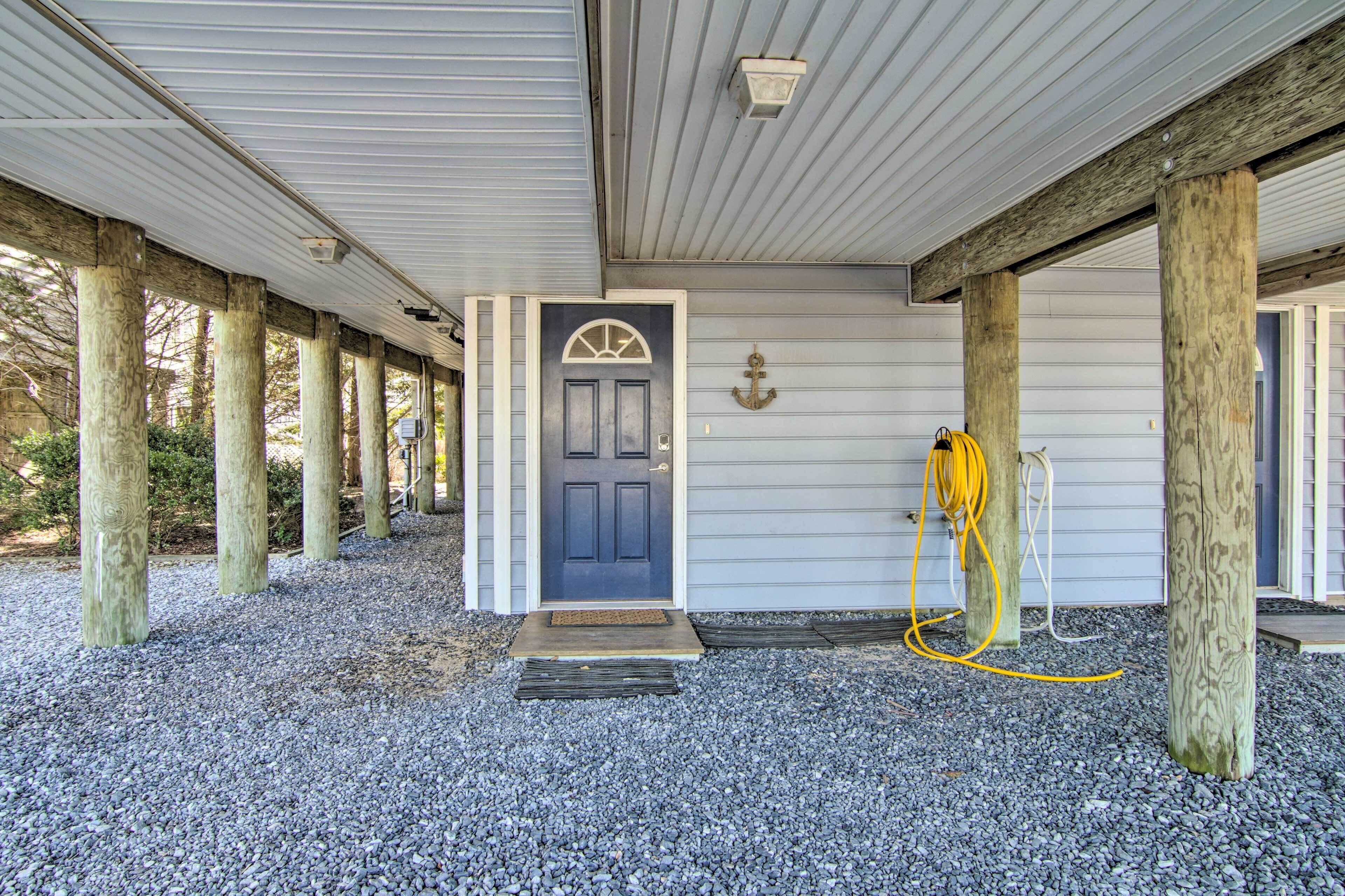 A covered porch with a door, wooden posts, and a hose on the ground.