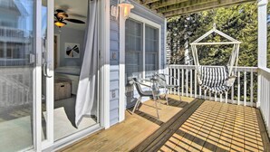 A covered porch with a wooden deck, a hanging chair, and a ceiling fan. - Bay-view Retreat w/ 5 Balconies in Bethany Beach! (Bethany Beach)