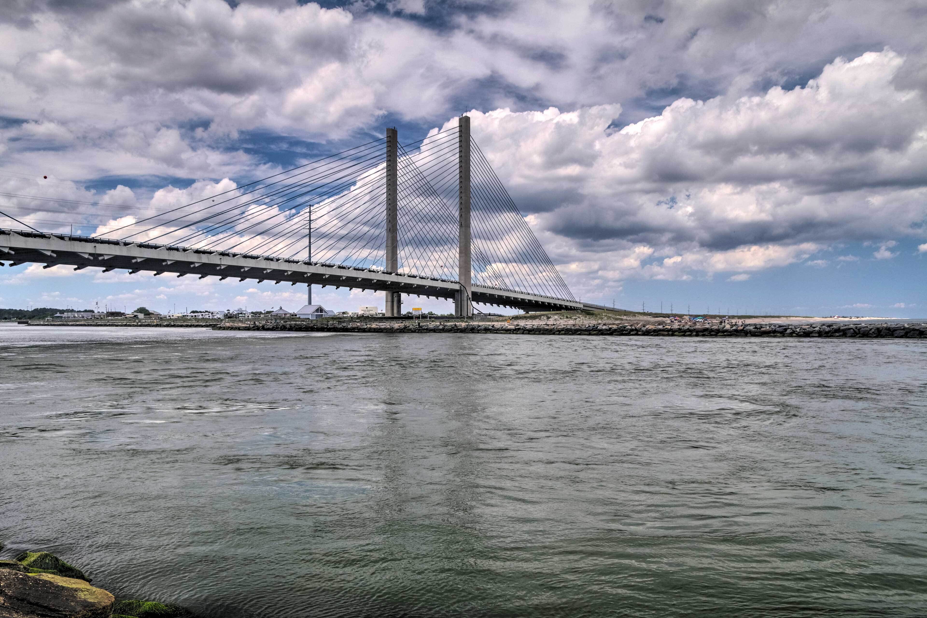 A large suspension bridge over a body of water with a cloudy sky in the background.