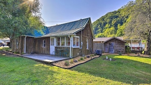 Une maison rustique en bois, dotée d’un grand porche, d’un patio couvert et offrant une vue sur une colline boisée.