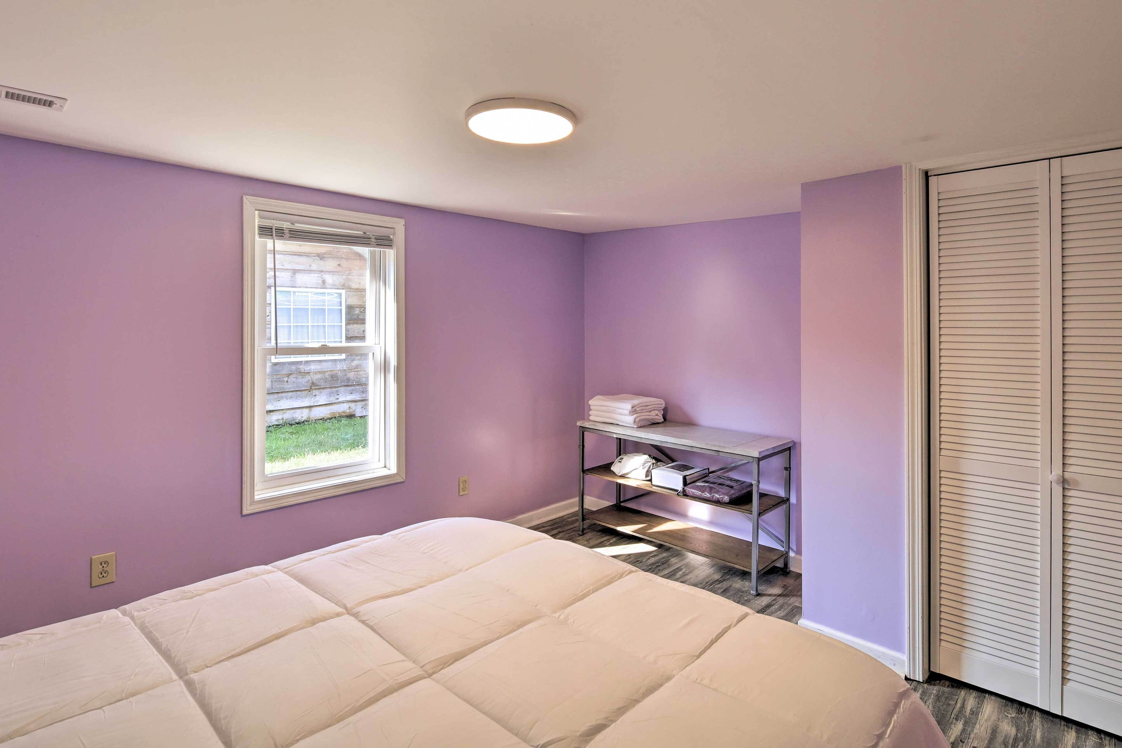 Ein Schlafzimmer mit Bett, Fenster, Ablage mit gefalteten Handtüchern und Schrank.