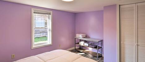 Ein Schlafzimmer mit Bett, Fenster, Ablage mit gefalteten Handtüchern und Schrank.