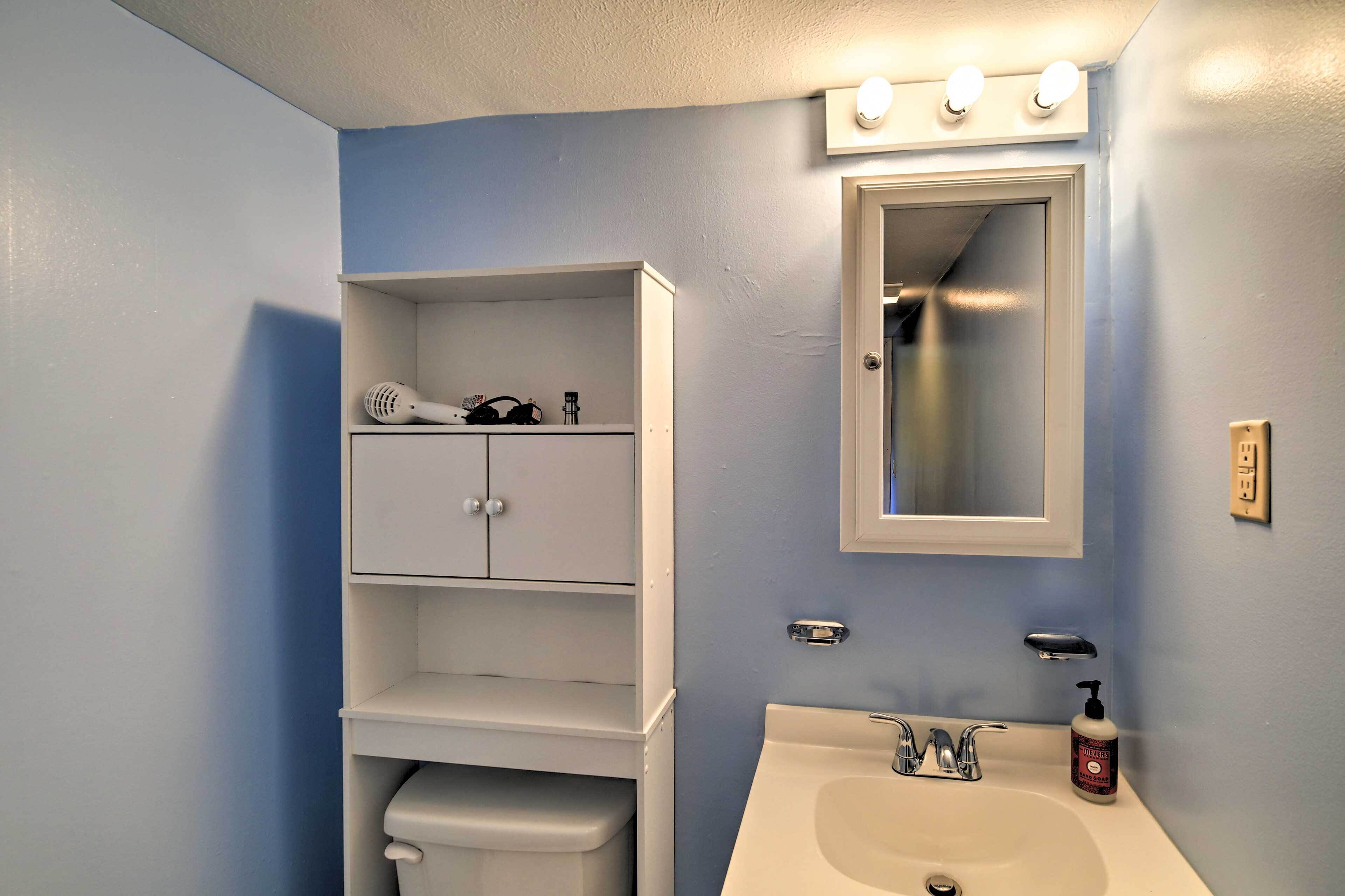 A bathroom with a white vanity, a mirror, and a sink.