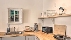 A kitchen with a wooden countertop, a coffee maker, a toaster, and a shelf with glasses and a blender. - Claires Cottage ~ 4 Mi to Downtown Greenville! (Greenville)