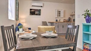 A dining area with a wooden table set for two, a blue chair, and a small table with a plant and a picture frame. - Claires Cottage ~ 4 Mi to Downtown Greenville! (Greenville)