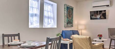 Un comedor con una mesa dispuesta para dos personas, un sofá azul, una mesita blanca y una alfombra estampada.