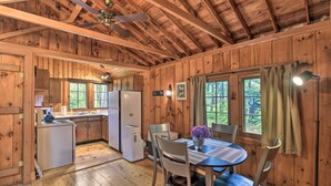 A wooden cabin interior with a kitchen, dining area, and a ceiling fan. - 'sprucewold' Boothbay Harbor Cottage w/ Deck (Boothbay Harbor)