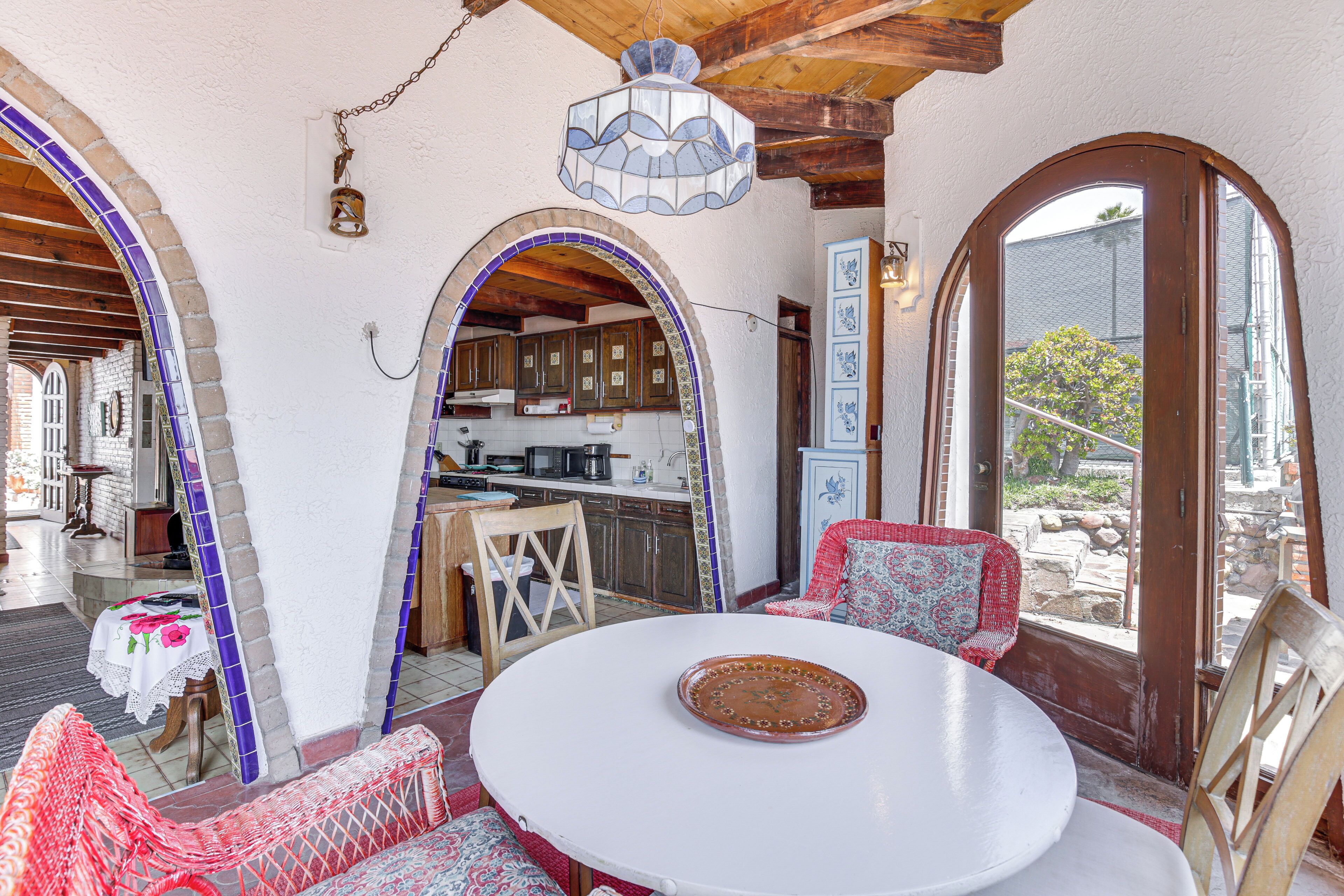 A dining area with a round table, chairs, and a view of the kitchen through an archway.