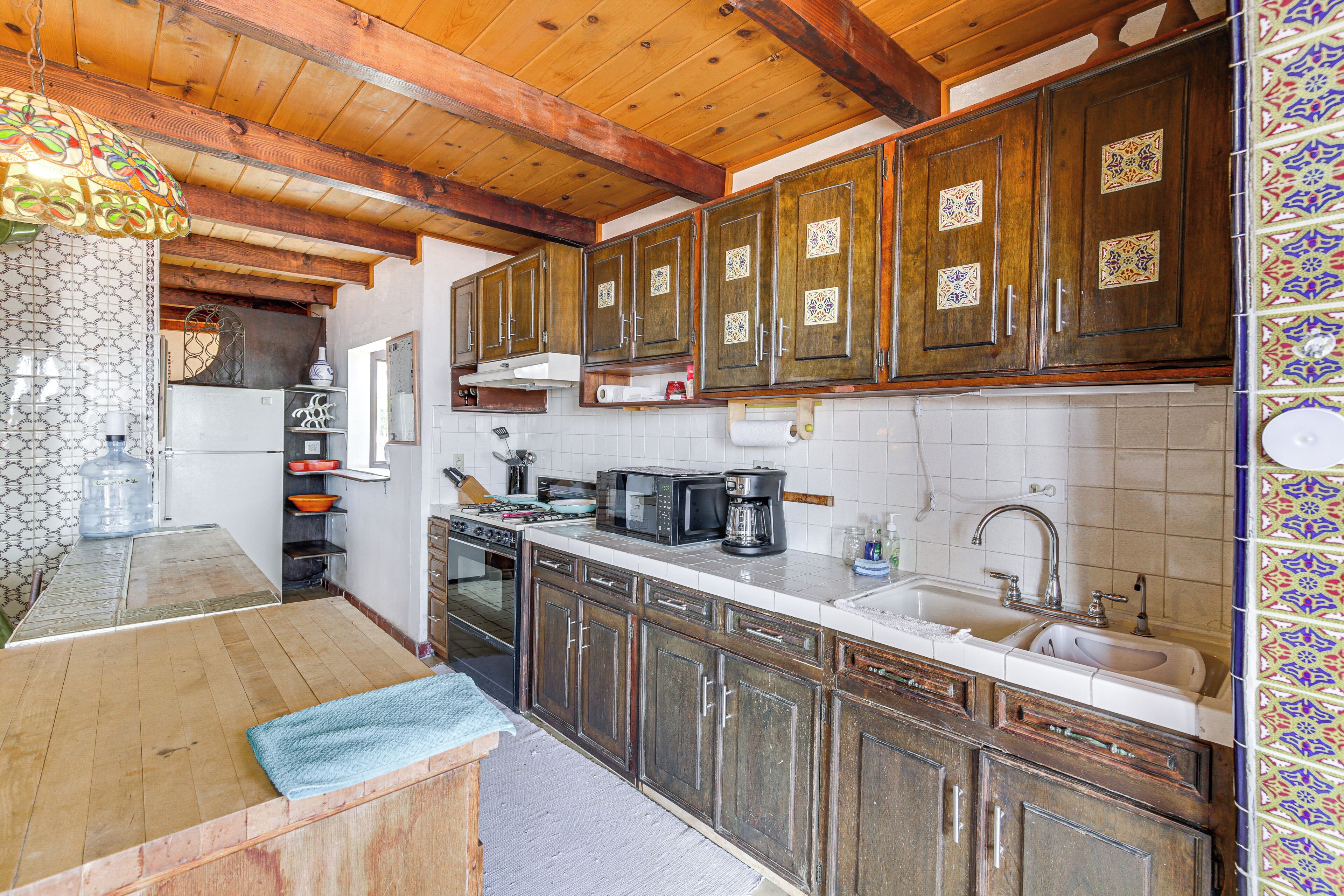 A kitchen with wooden cabinets, a microwave, a sink, and a tiled backsplash.