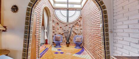A room with a tiled floor, two blue chairs with cushions, a wooden bench, and a skylight.