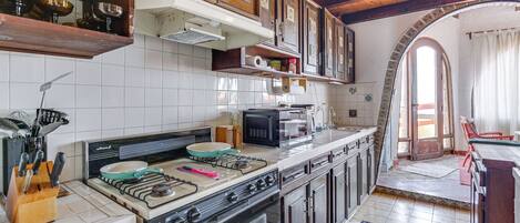 A kitchen with wooden cabinets, a stove, a microwave, and a tiled backsplash.