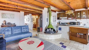 A spacious living area with a blue sofa, a round coffee table, and a fireplace. The kitchen features wooden cabinets and a microwave. - Rosarito Beach Home in Las Gaviotas w/ Ocean Views (Playas de Rosarito)