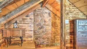 A rustic room with a wooden desk, stone wall, and a dresser. - Peaceful Log Cabin Escape Near Table Rock Lake! (Golden)