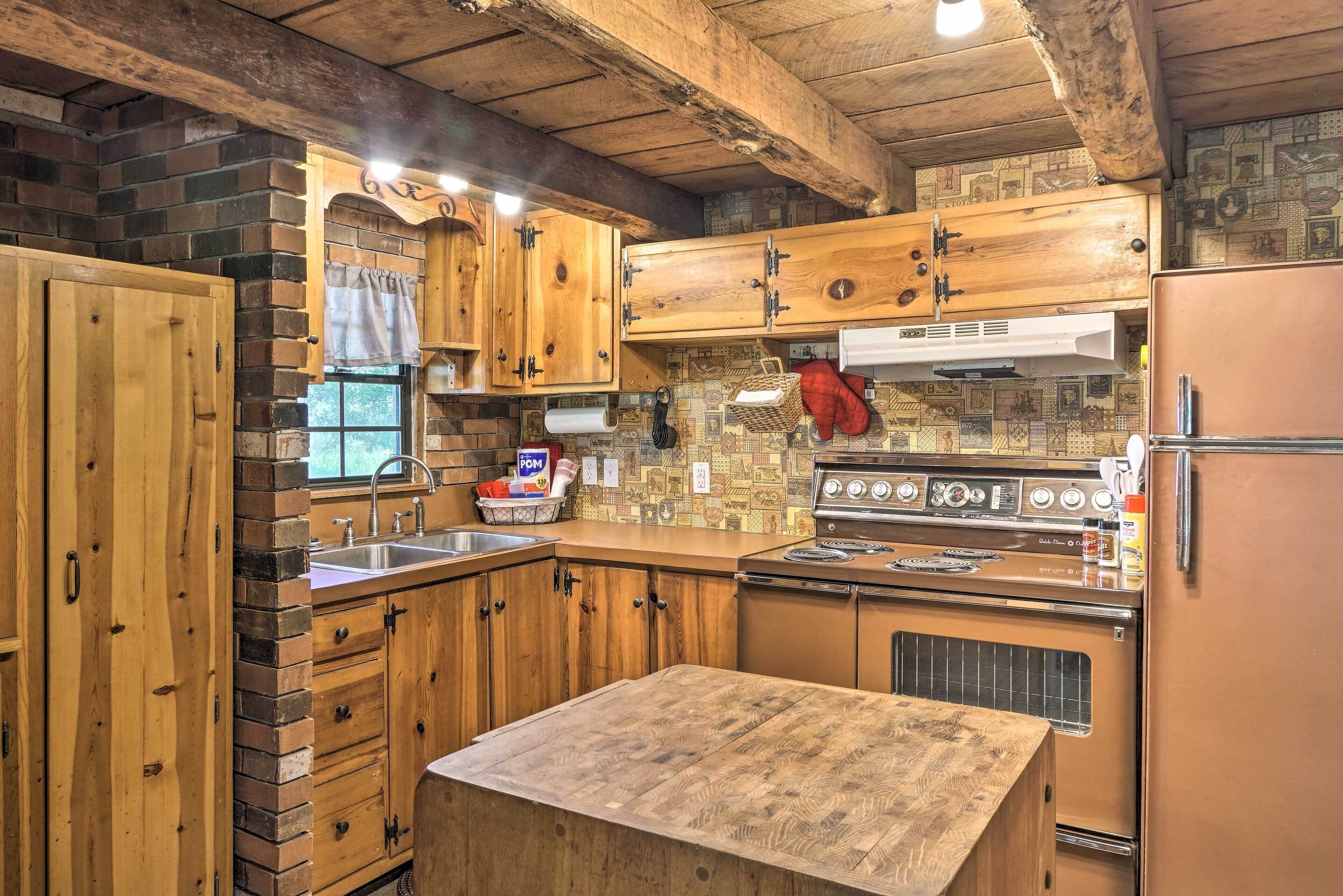 Una cocina rústica con armarios de madera, pared de ladrillo, estufa y refrigerador.
