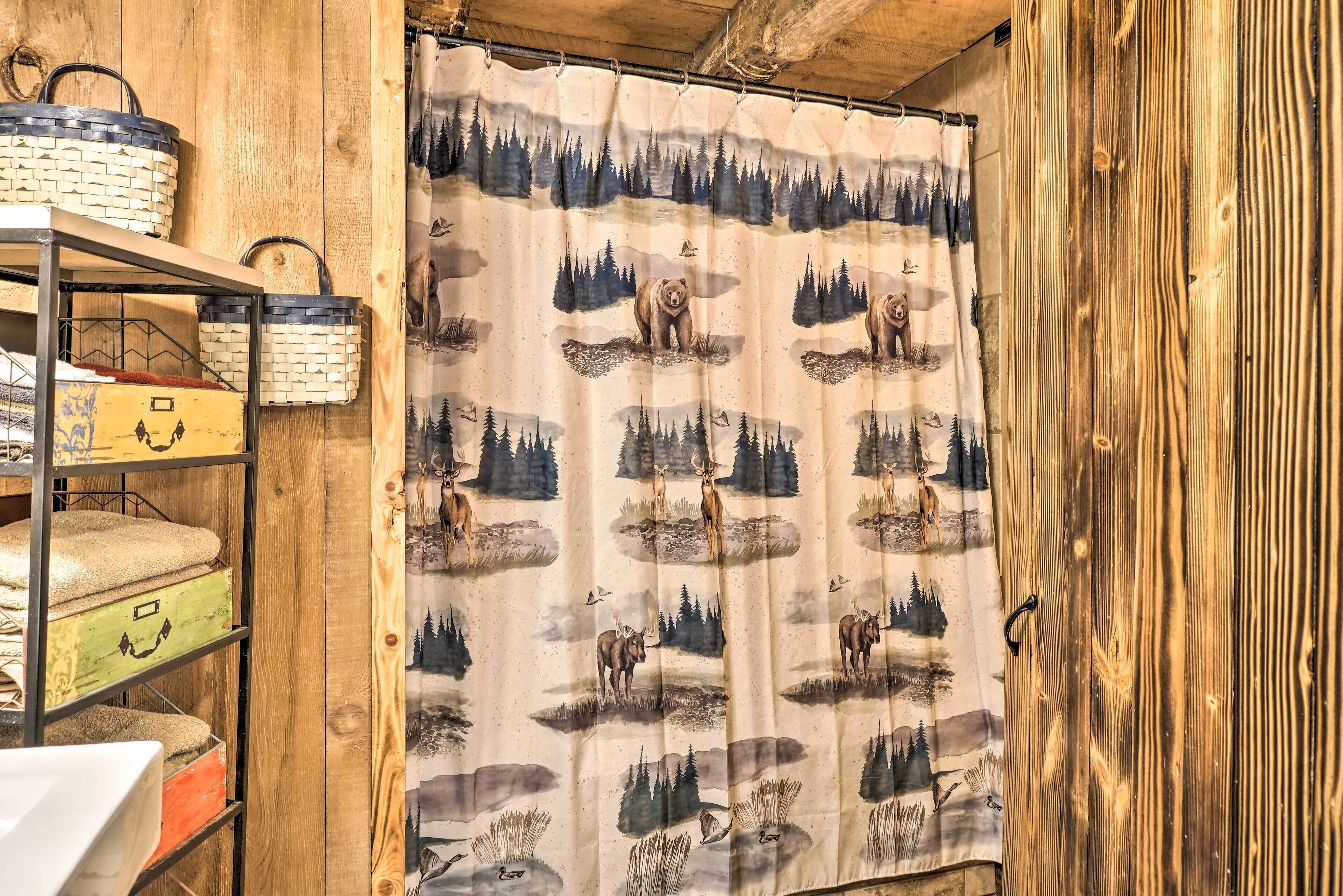 A rustic room with a wooden wall, a curtain with a forest and wildlife print, and a shelf with baskets and storage boxes.