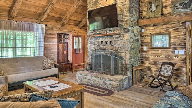 A rustic cabin interior with a stone fireplace, wooden ceiling, and a cozy seating area. - Peaceful Log Cabin Escape Near Table Rock Lake! (Golden)
