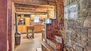 A rustic kitchen with wooden beams, stone walls, and a built-in wood stove. - Peaceful Log Cabin Escape Near Table Rock Lake! (Golden)