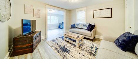 A living room with a television, a sofa, a coffee table, and a rug.