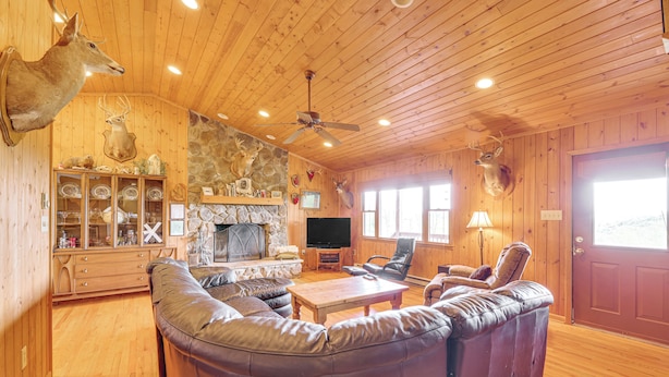 A wooden interior with a leather sofa, a television, and mounted animal heads. - Fish, Hike, Hunt: Secluded Cabin in Doe Hill! (Doe Hill)