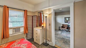 A bedroom with a bed, a dresser, a standing lamp, and a window with curtains. - 'St Patrick' Apartment in the Heart of Bisbee (Bisbee)