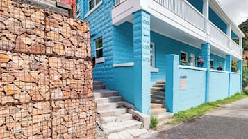 A two-story building with a stone wall on the left and a blue facade.