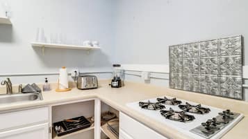 Una cocina con estufa, tostadora y diferentes utensilios.