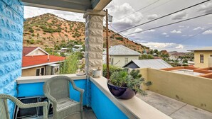 A balcony with wicker chairs, a potted plant, and a view of a hilly landscape. - 'St Patrick' Apartment in the Heart of Bisbee (Bisbee)