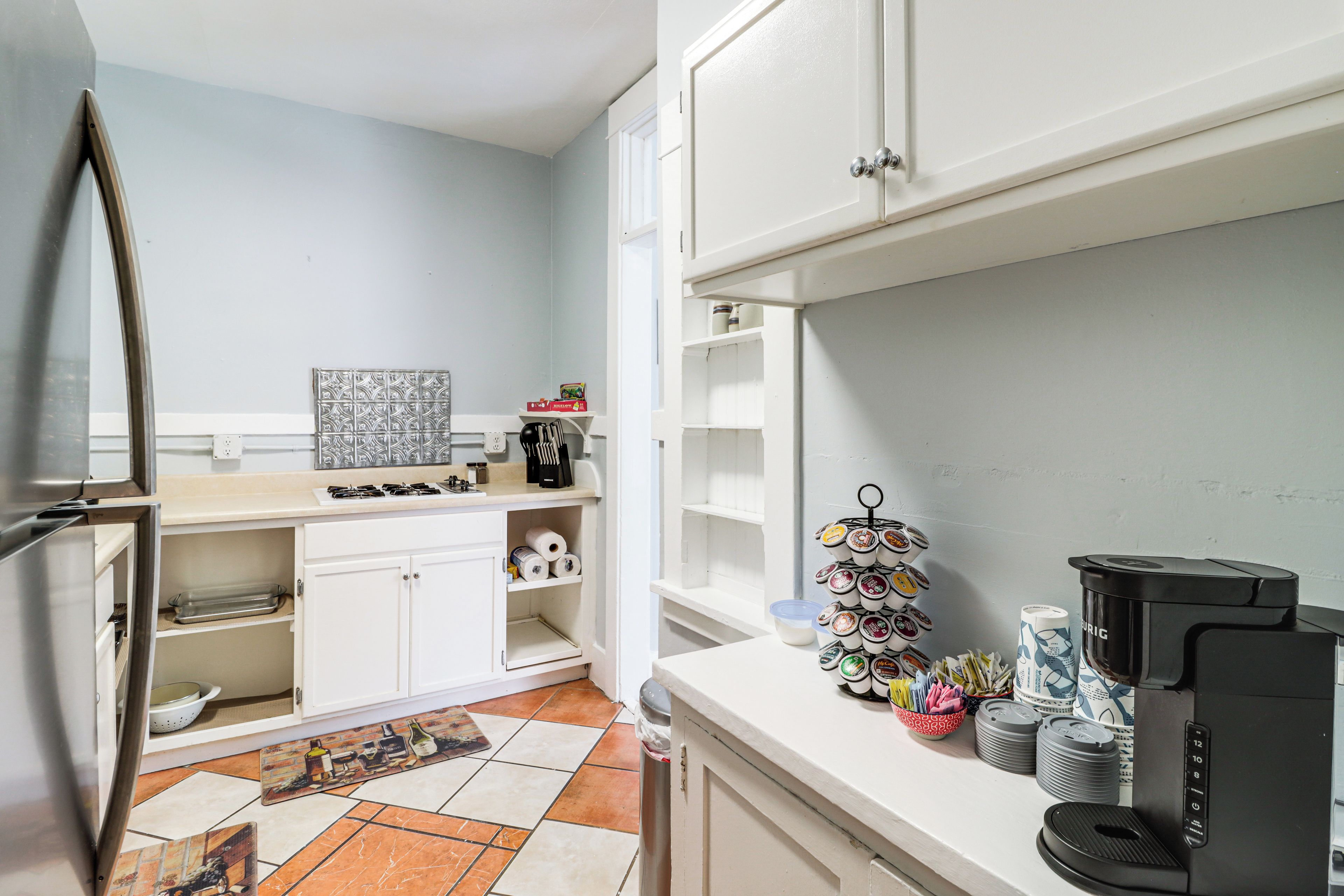 A compact kitchen with white cabinets, a gas stove, and a coffee machine.