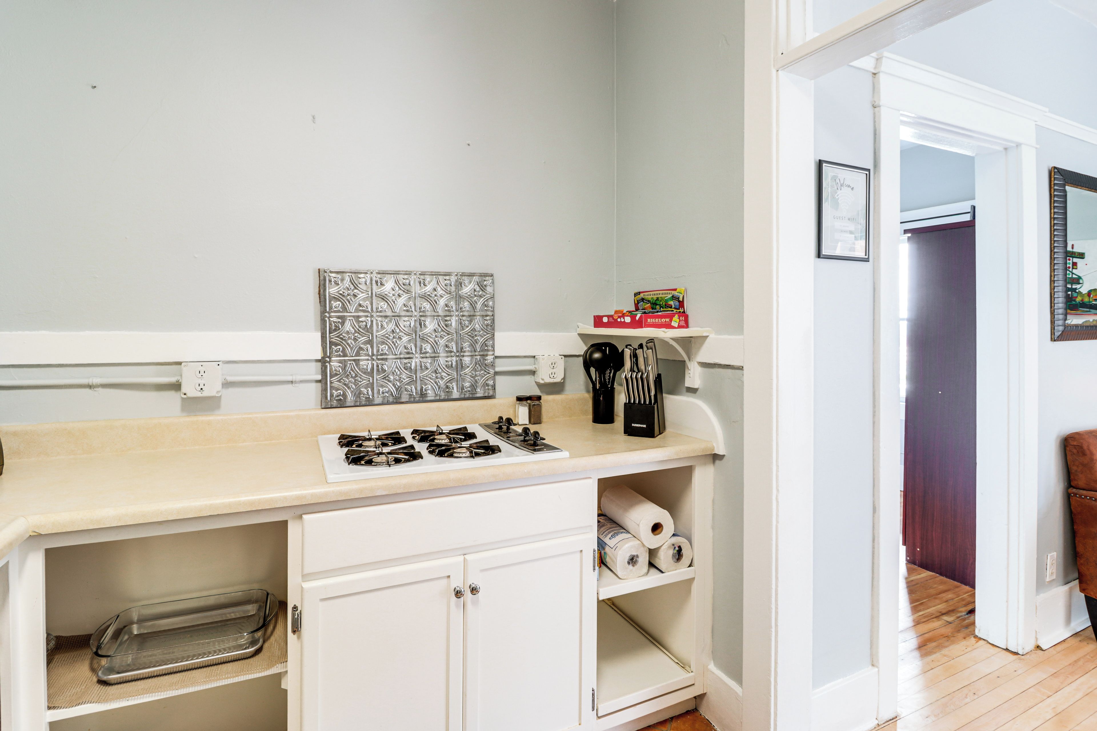 A kitchen with a white countertop, a decorative backsplash, and a roll of paper towels.