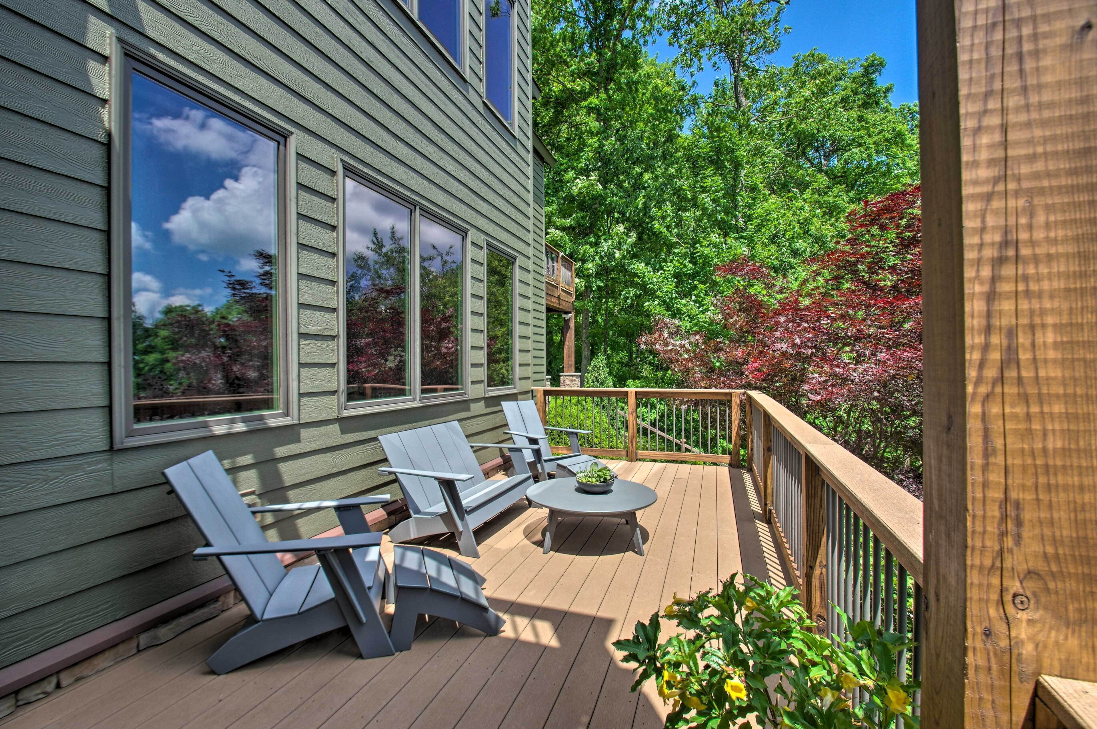A deck with two Adirondack chairs and a small table, surrounded by a wooden railing.