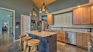 A modern kitchen with a central island, wooden cabinets, stainless steel appliances, and a hanging light fixture. - Grand Chalet w/ Hot Tub - Near Wintergreen Resort (Nellysford)