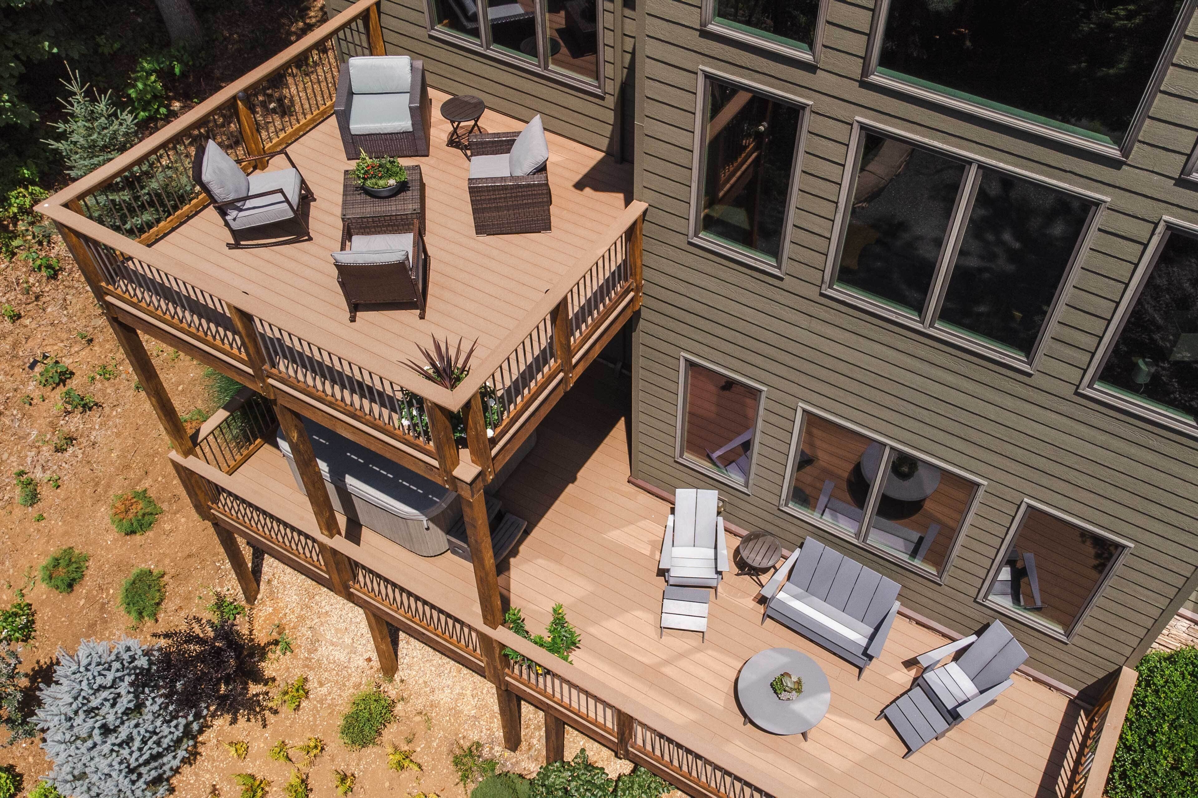 A two-story house with a deck, outdoor seating, and large windows.
