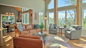 A spacious living room with a large window, a dining area, and a cozy seating arrangement. - Grand Chalet w/ Hot Tub - Near Wintergreen Resort (Nellysford)