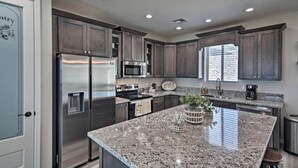 A modern kitchen with granite countertops, stainless steel appliances, and dark wood cabinets. - Luxe Home w/ OHV Access, 5 Mi to Lake Mohave! (Bullhead City)