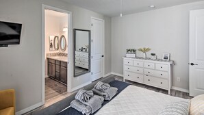 A bedroom with a bed, a dresser, a mirror, and a television on the wall. - Luxe Home w/ OHV Access, 5 Mi to Lake Mohave! (Bullhead City)