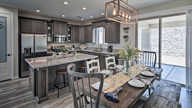 A modern kitchen with dark wood cabinets, stainless steel appliances, and a large island with bar stools. - Luxe Home w/ OHV Access, 5 Mi to Lake Mohave! (Bullhead City)