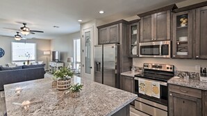 A modern kitchen with granite countertops, stainless steel appliances, and dark wood cabinets. - Luxe Home w/ OHV Access, 5 Mi to Lake Mohave! (Bullhead City)