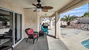 A covered patio with a ceiling fan, sliding glass doors, outdoor seating, and a pool. - Lake Havasu City Retreat w/ Patio & Grill (Lake Havasu City)
