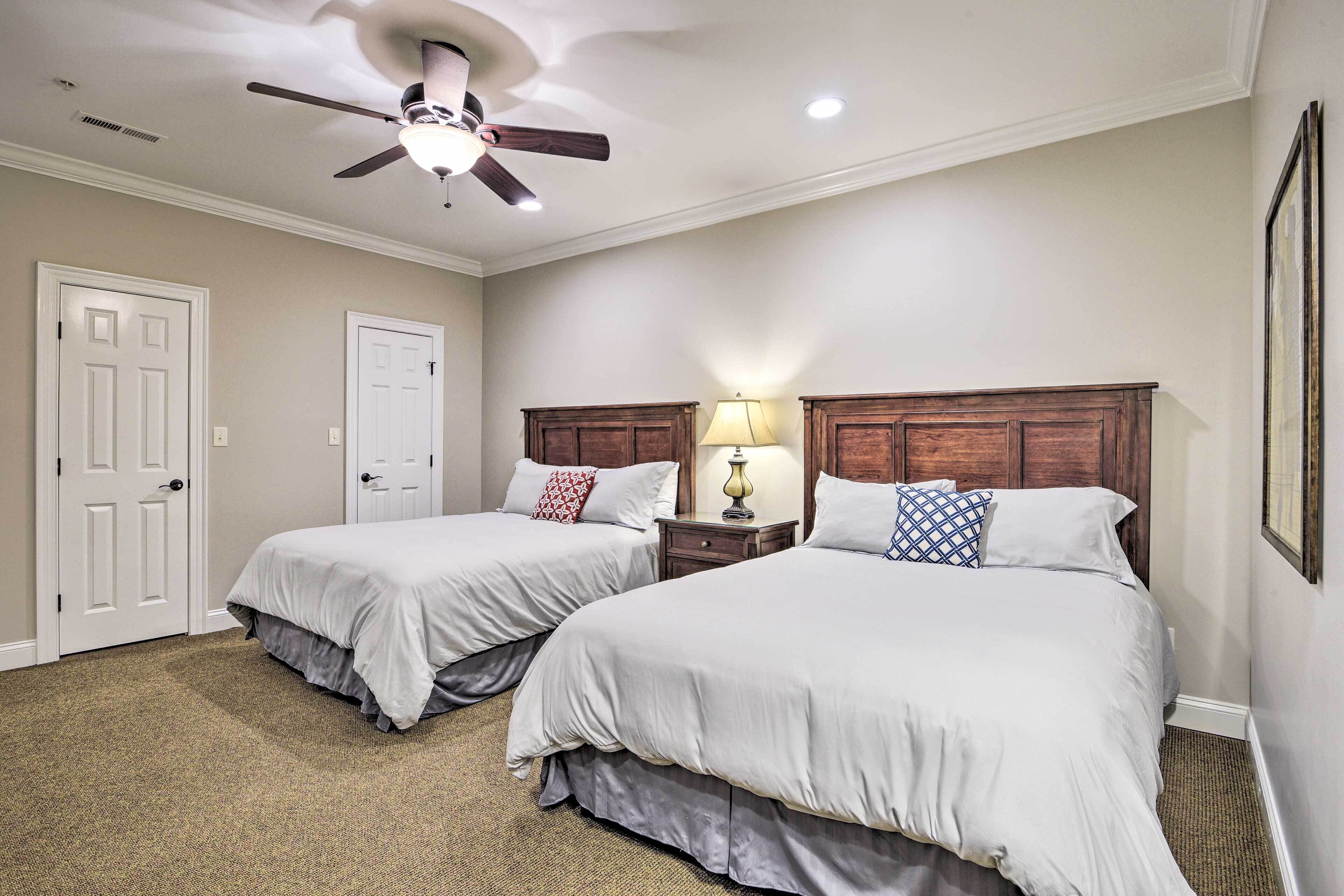 A hotel room with two beds, a ceiling fan, and a nightstand with a lamp.