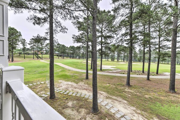A view of a golf course with tall pine trees and a well-maintained lawn.