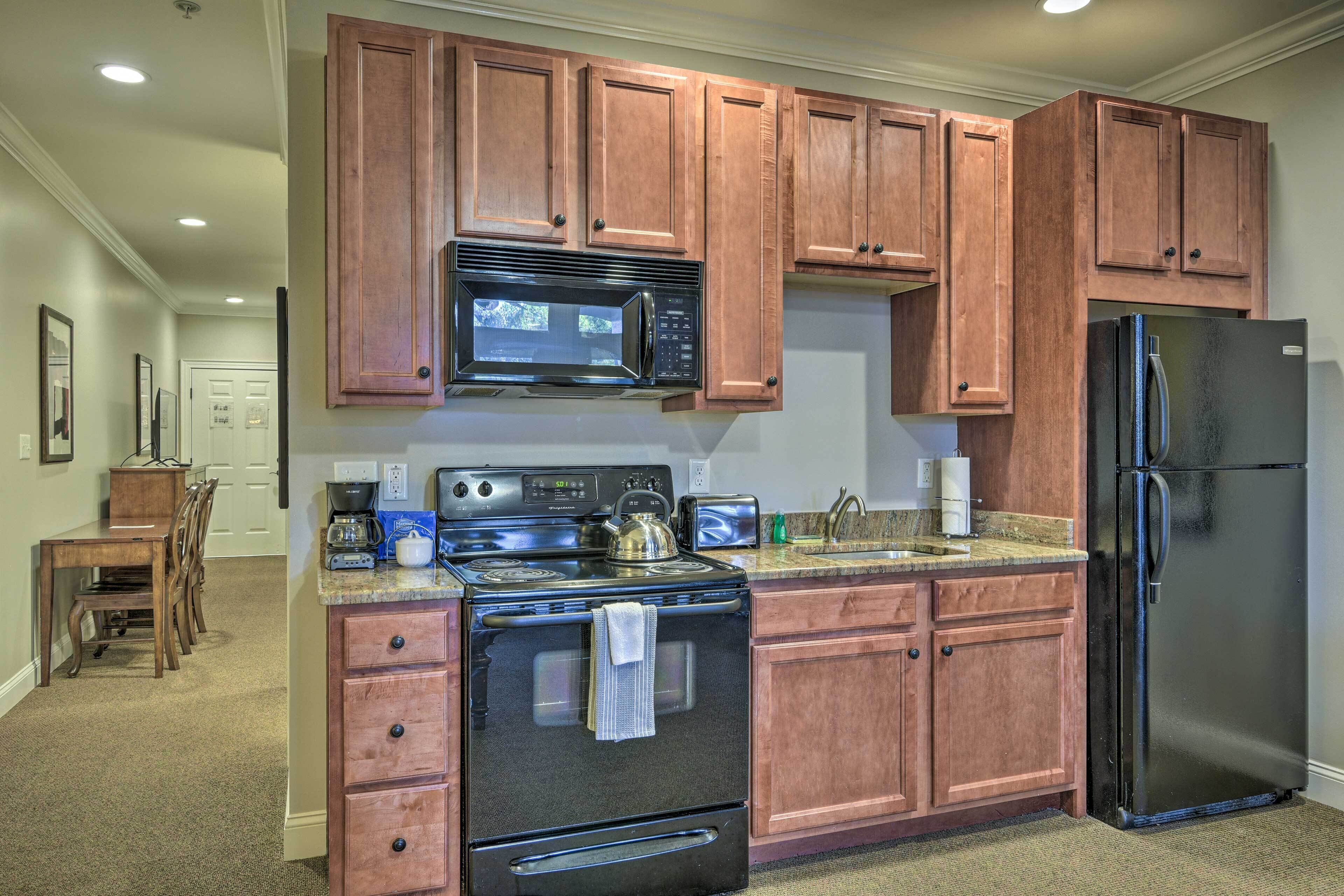 A kitchen with wooden cabinets, a stainless steel refrigerator, a microwave, a stove, and a toaster.