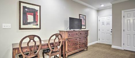 A room with a desk, two chairs, a dresser, and a television.