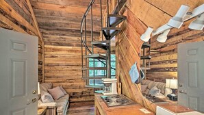 Ein rustikales Blockhaus-Interieur mit Holzboden, einer Couch, einer Küchenzeile mit Herd und einem großen Spiegel.