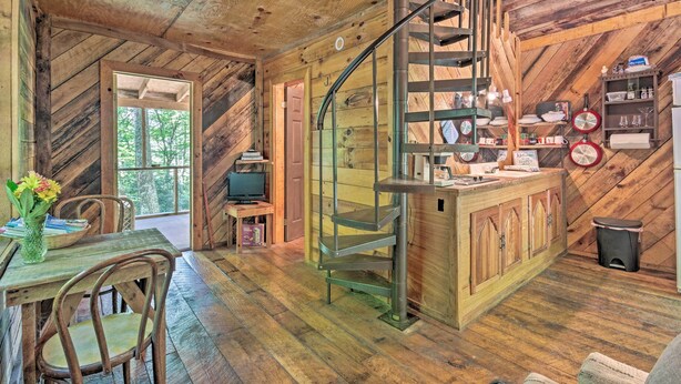 Ein rustikales Blockhaus-Interieur mit einer Holzspirale, einem Essbereich mit Tisch und Stühlen sowie einer Küchenzeile mit diversen Gegenständen.