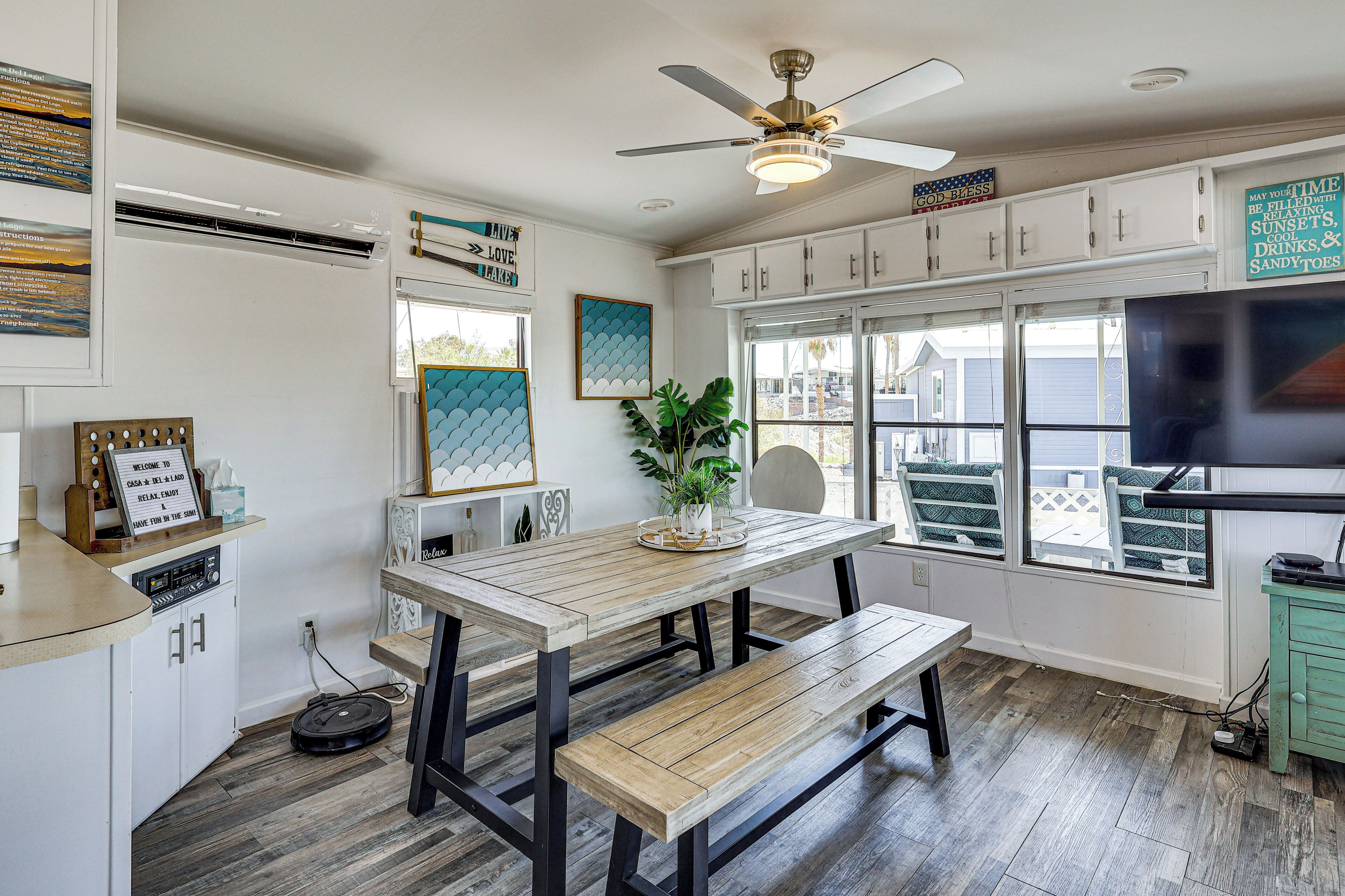 A kitchen with a wooden table, bench, ceiling fan, and cabinets.