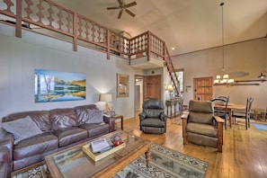 A spacious living room with a leather sofa, a glass coffee table, and a painting on the wall.
